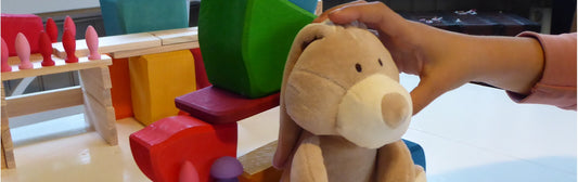 Barnhand som griper efter hållbart gosedjur bland andra giftfria leksaker.